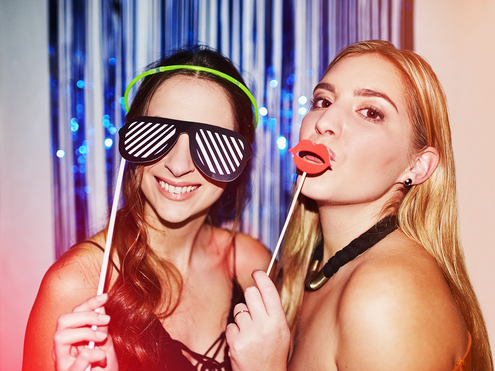 TGIF. Shot of two beautiful young women having fun with props in a photobooth.